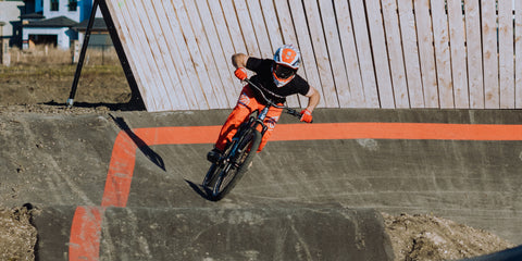 Professional downhill mountain bike racer and pump track world record holder Jason Connor rides his bike at a paved pump track.