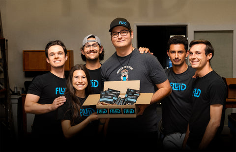 Group of people holding a box with Fluid products in an indoor setting