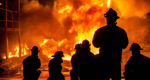 Firefighters silhouetted against a large fire