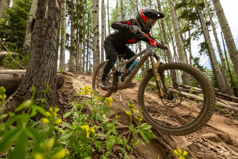 Pro enduro rider Porsha Murdock rides her mountain bike down a trail in a forest.