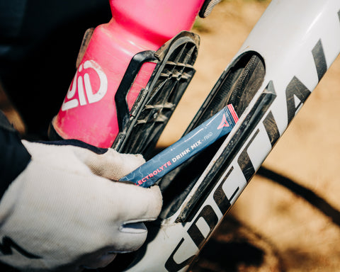 Close-up of a bicycle with a pink bottle and Tactical EDM, held by a gloved hand.